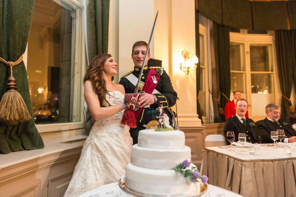 bride and groom using a ceremonial sword to cut their wedding cake in The Holyrood Suite
