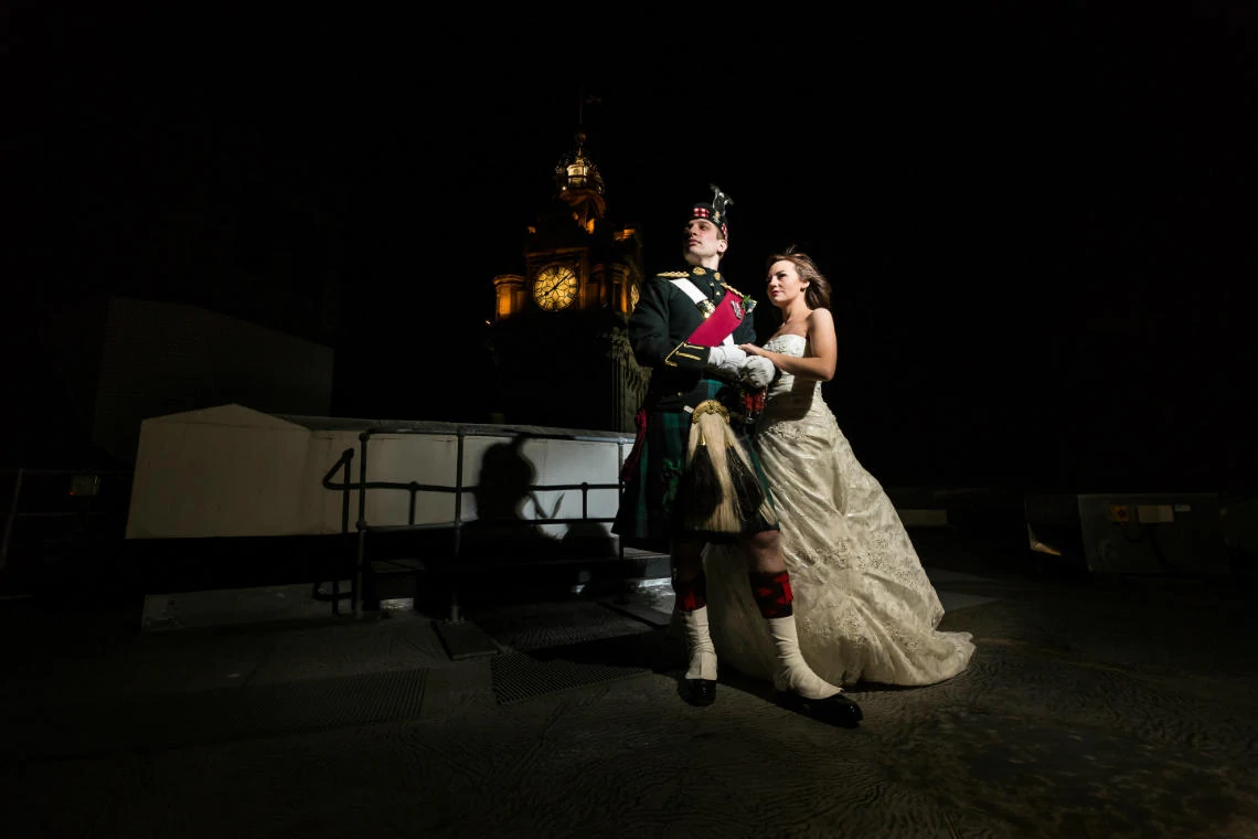 bride and groom on the roof of the Balmoral Hotel at night with the grand clock in the background