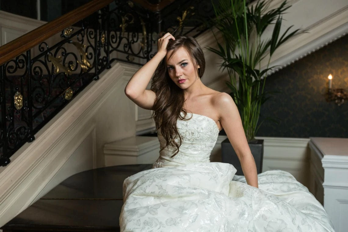 bride sitting on the piano at the foot of the staircase in the Balmoral Hotel