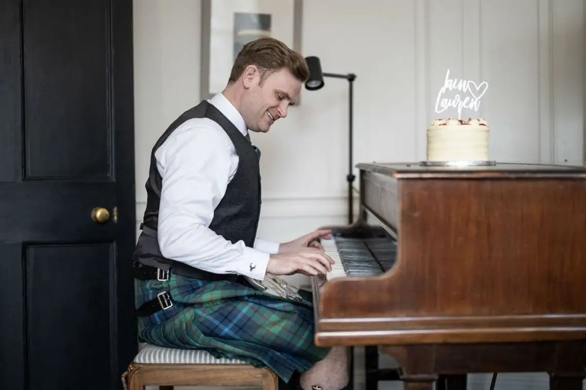 Groom wearing a kilt playing the piano