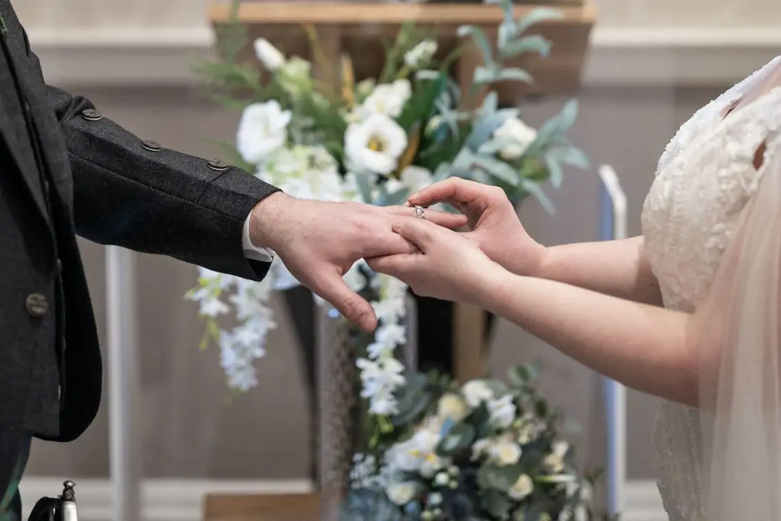 Bride placing ring on groom's finger