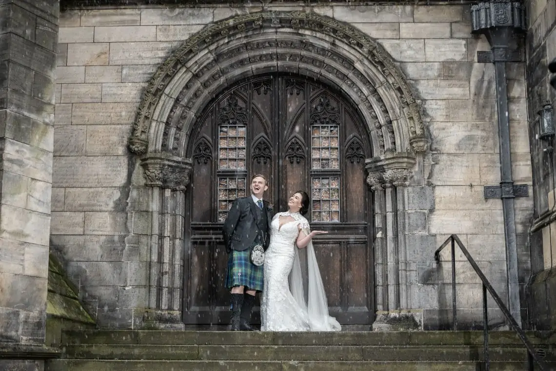 Newlyweds standing in the sleet on the steps at the back of St Giles' Cathedral