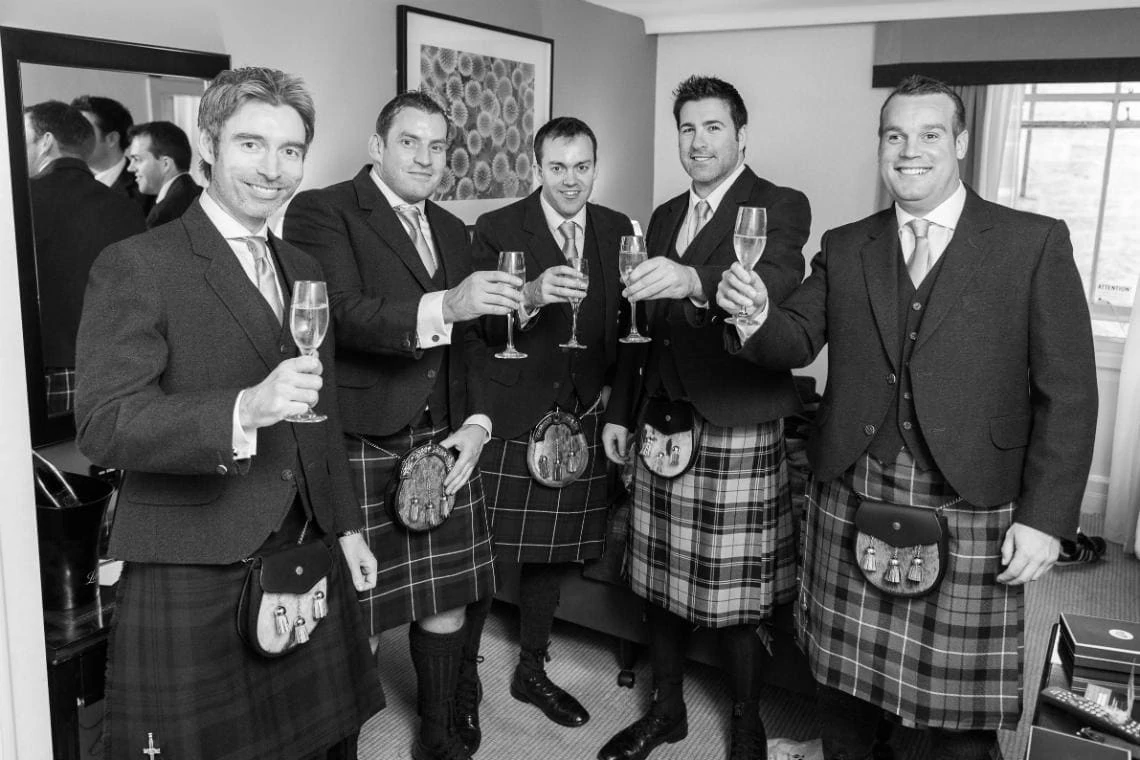 groom and ushers raising a toast in a bedroom