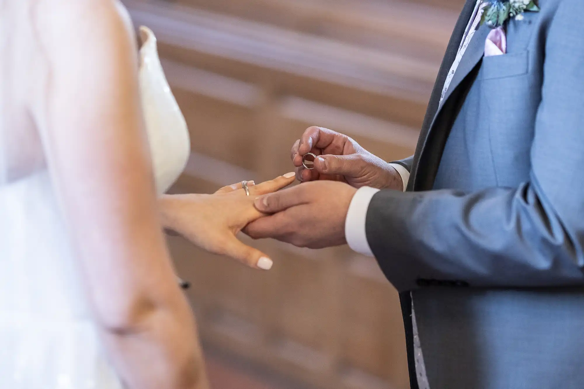 A groom places a wedding ring on the bride's finger during a wedding ceremony.