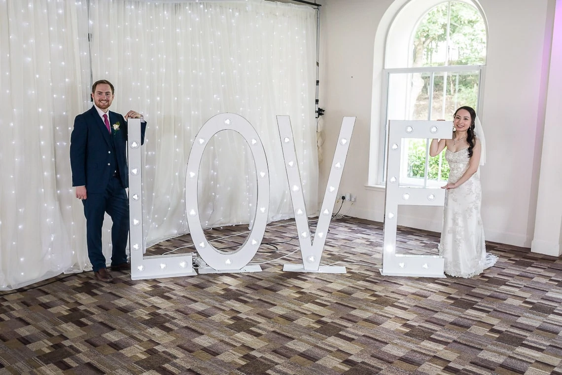Newlyweds standing with the big LOVE letters sign.