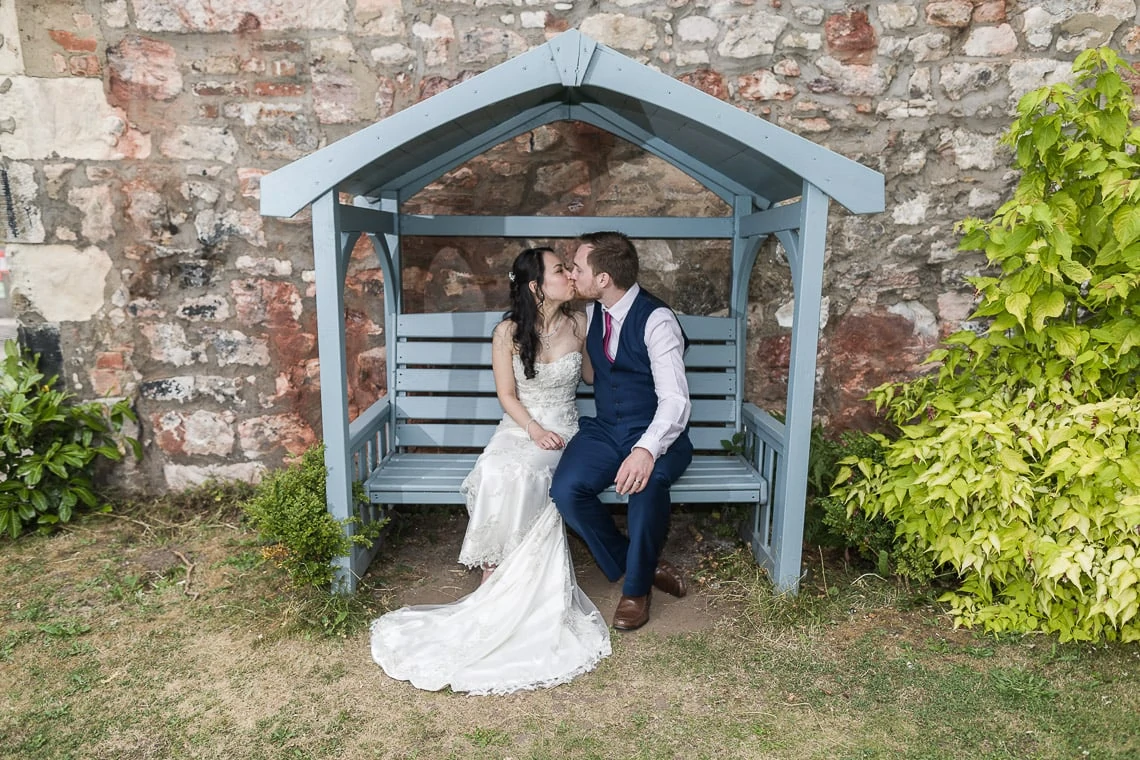 Newlyweds embrace on a chair in the garden.