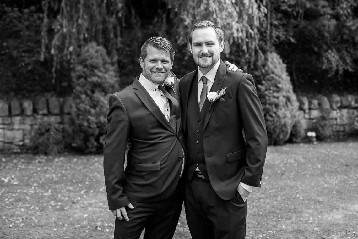 posed black and white of groom with bestman in garden