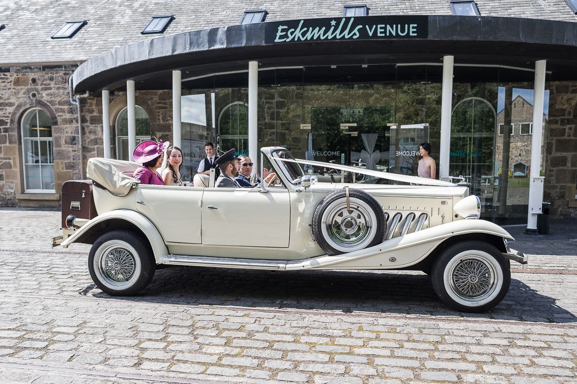 photo of bride with her parents in wedding car outside wedding venue