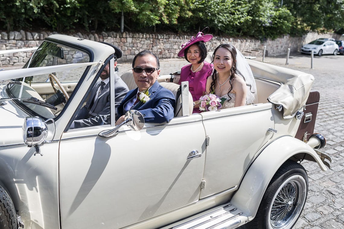 photo of wedding car with bride and her parents arriving at wedding venue