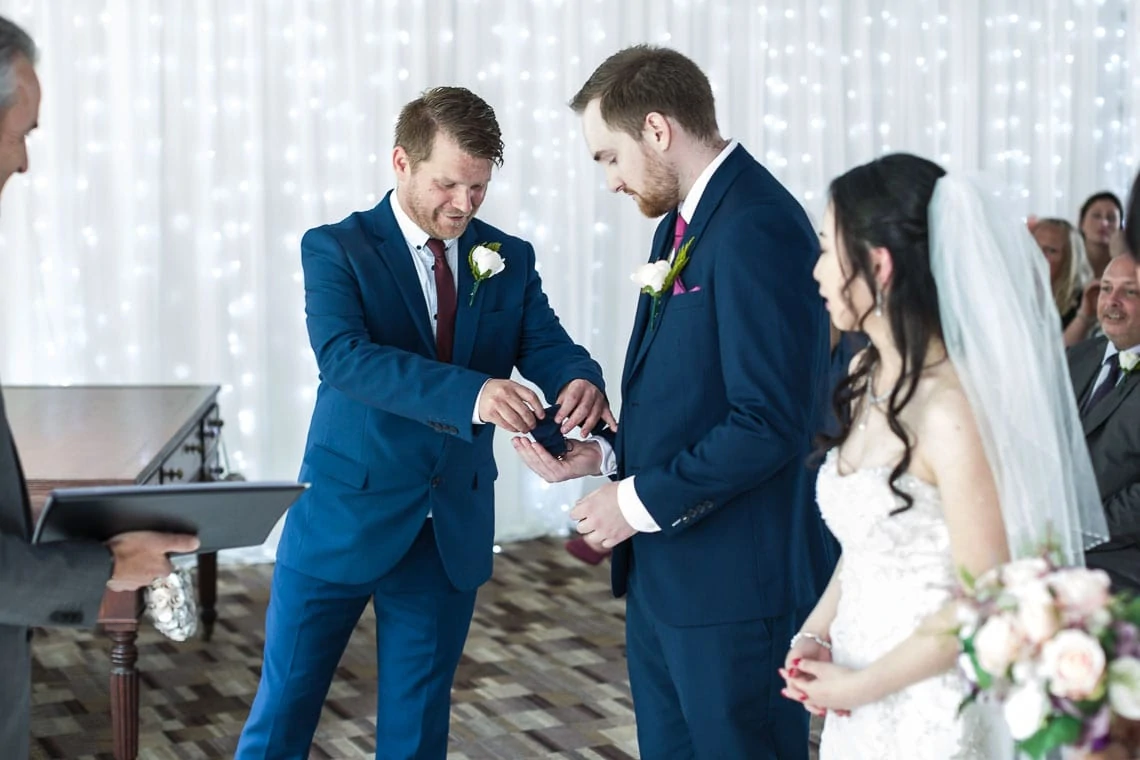 bestman giving wedding rings to groom