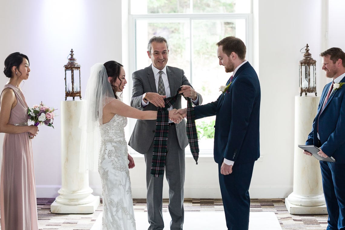 bride and groom with humanist celebrant as they tie the knot during wedding ceremony