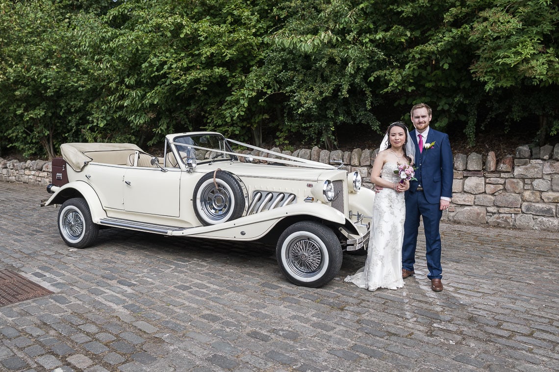 newlyweds in front of Beauford wedding car
