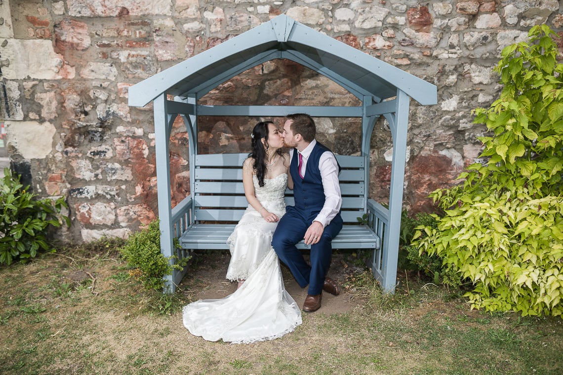 Eskmills Venue Wedding newlyweds kissing on bench in garden