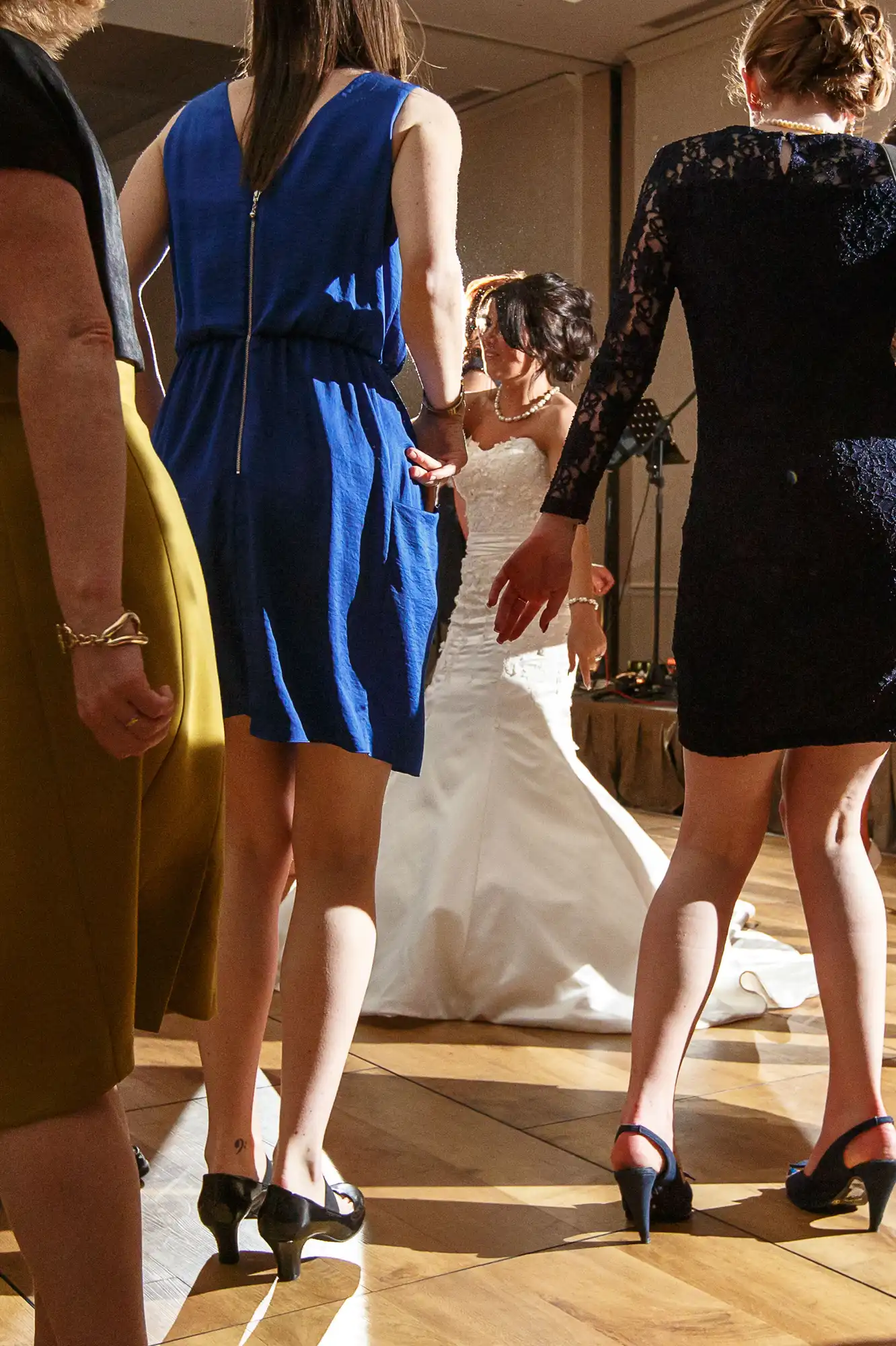 A bride dancing surrounded by guests in elegant attire at a wedding reception.