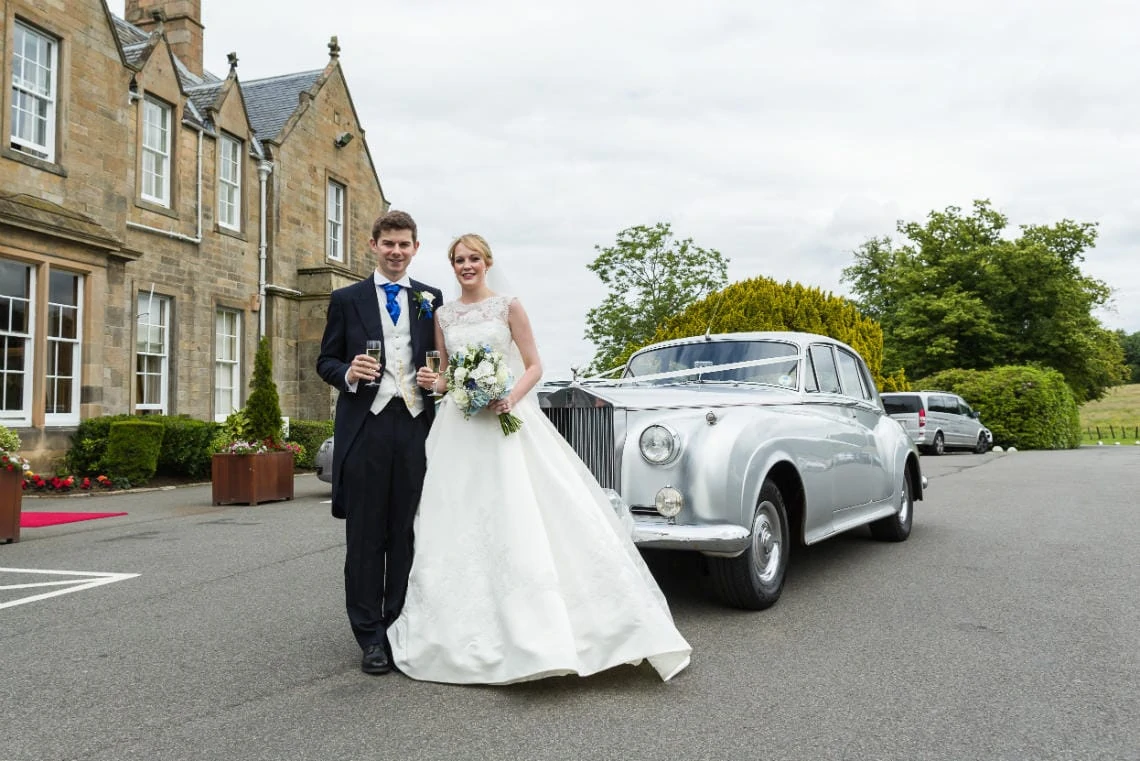 Garden newlyweds in front of their classic car