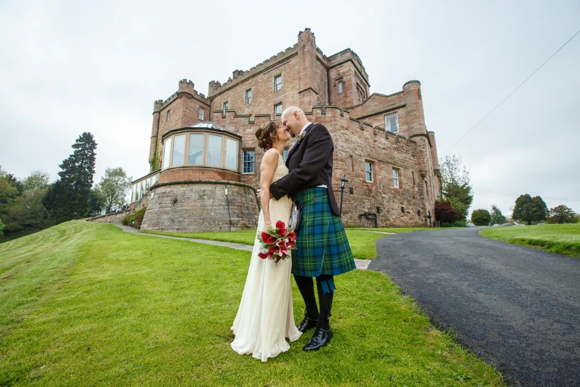 Gardens - bride and groom embrace with castle in the background
