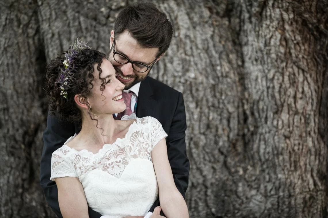 Gardens - newlyweds embrace in front of a large tree