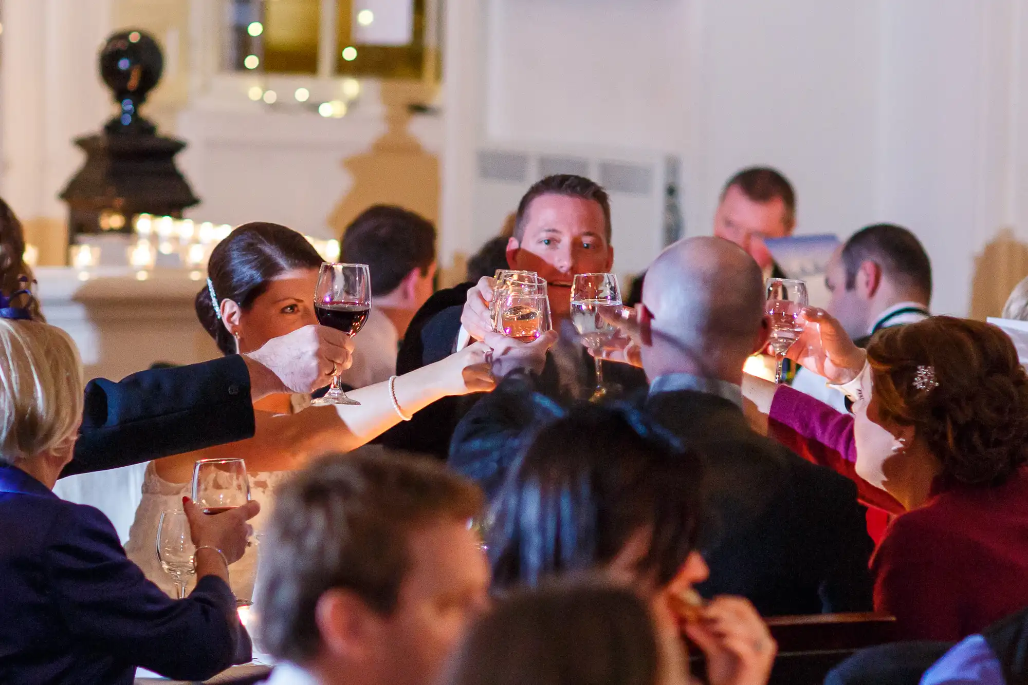 People at a formal event toasting with wine glasses in a warmly lit room.
