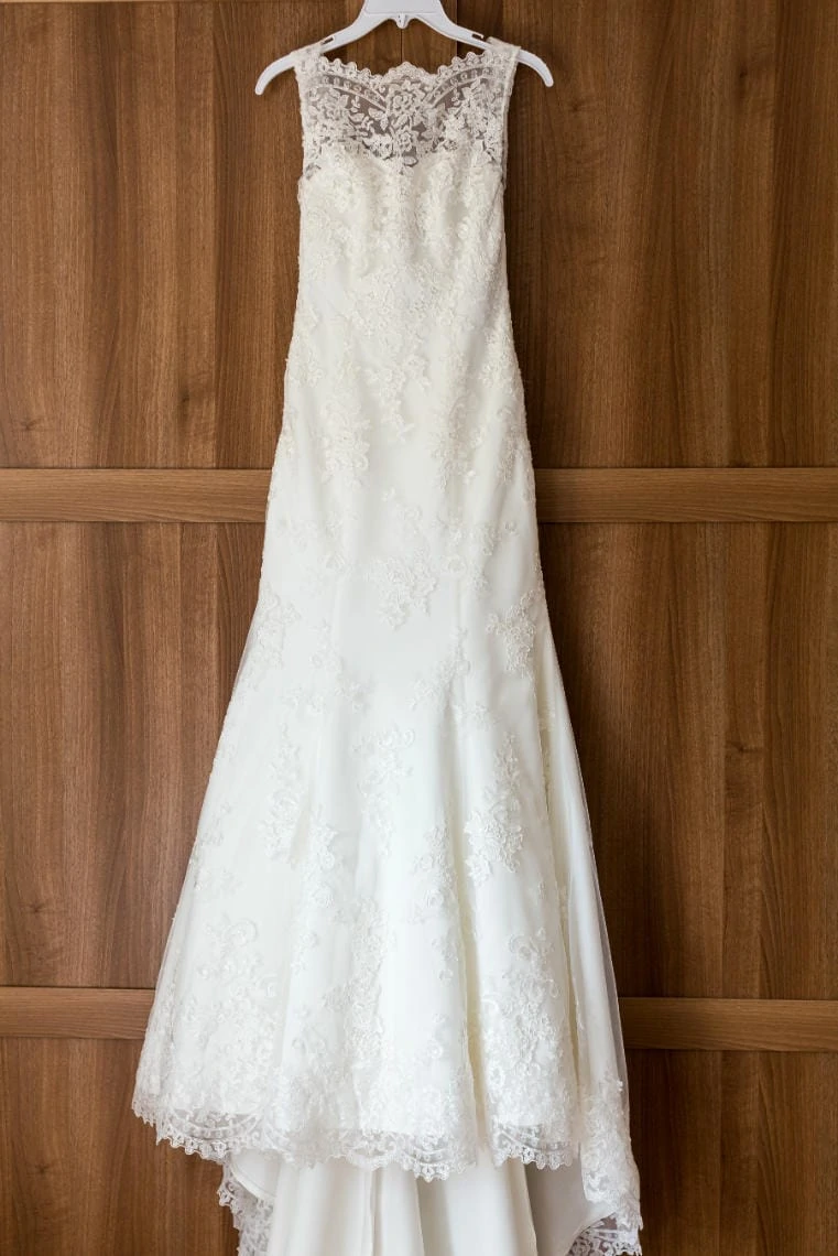 bride's full-length white wedding dress hanging on a wooden wardrobe