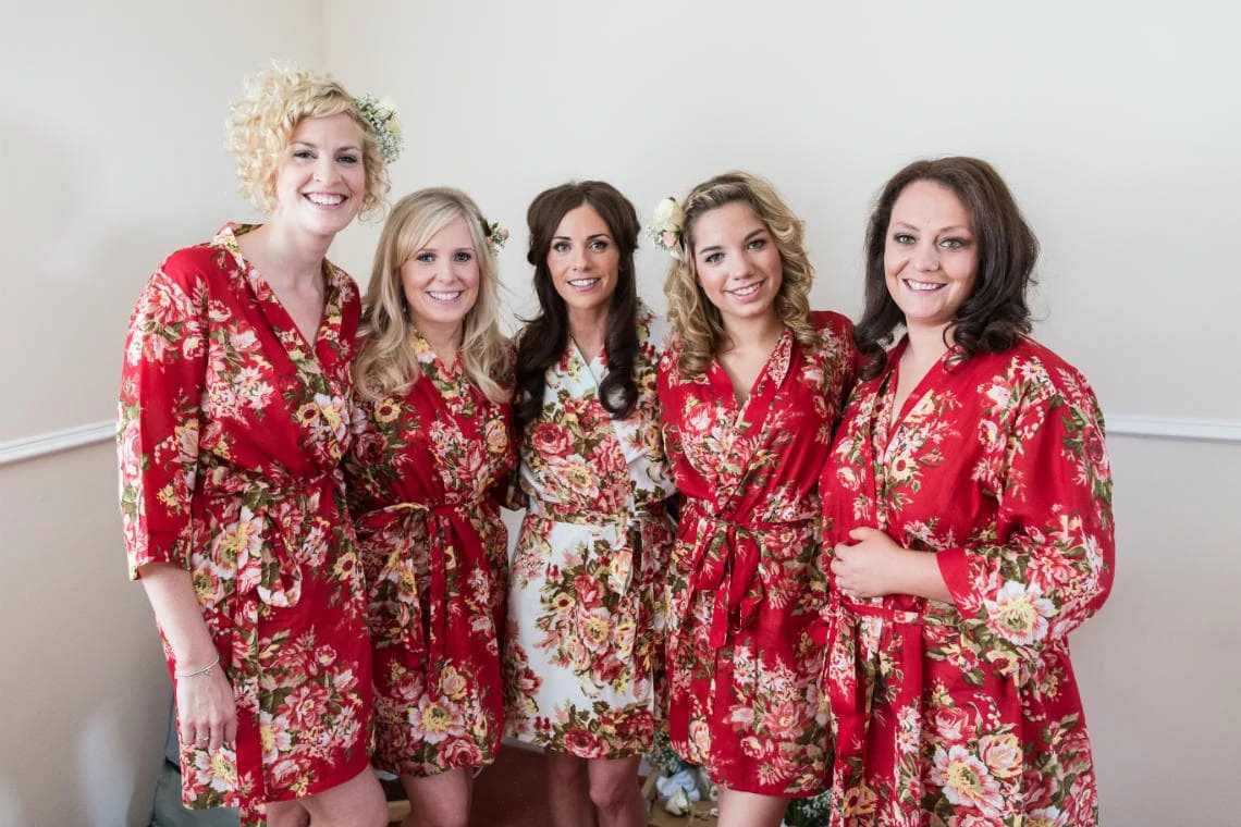 bride and bridesmaids group photo during the pre-ceremony preparations all wearing flower robes