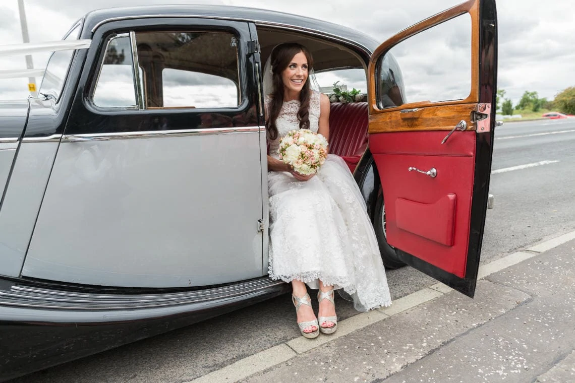 bride exiting a classic wedding car outside the church