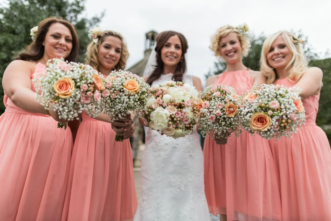 bride and bridesmaids showing their bouquets outside the church in East Lothian