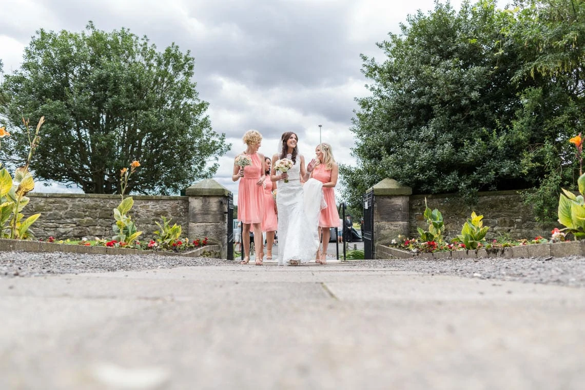 bride is escorted by her bridesmaids as they make their way up the path into the church in East Lothian