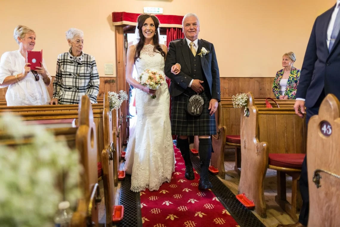 bride escorted by her father up the aisle during the processional at the church