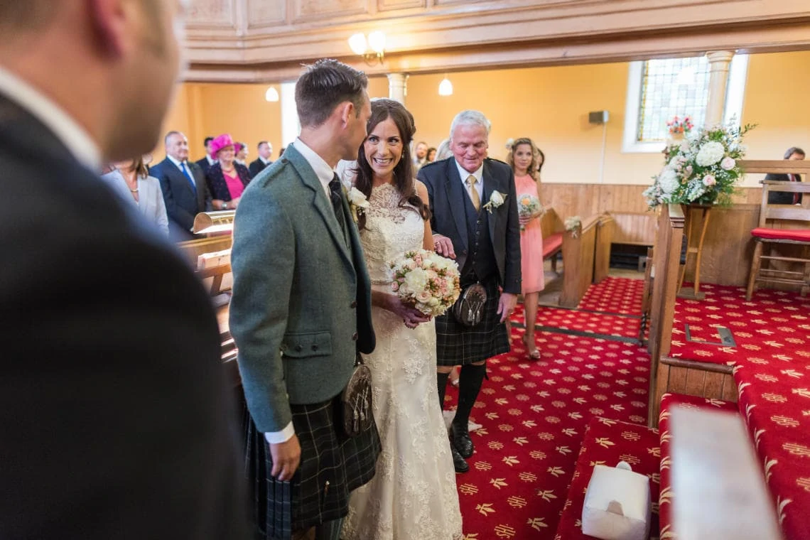 bride smiles at her groom as she arrives to get married at the church in East Lothian