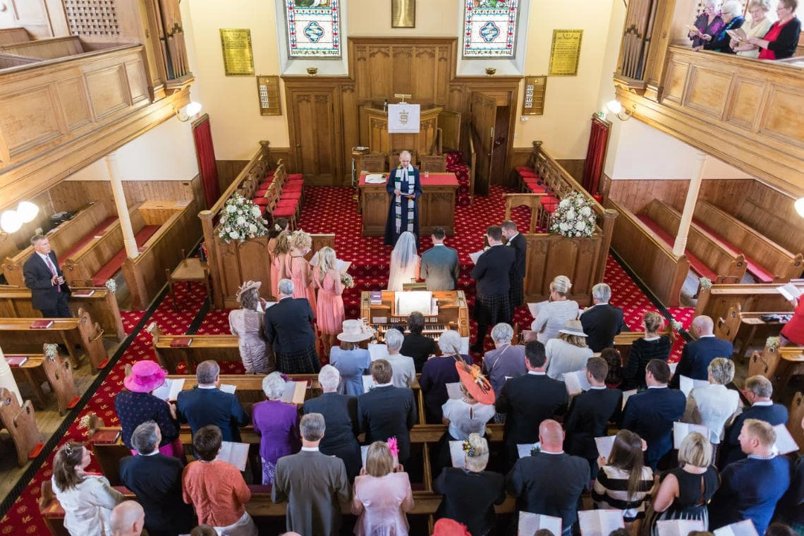 view from the rear balcony of hymn singing during the wedding ceremony at the church in East Lothian