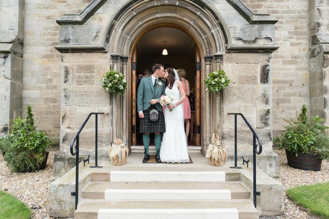 newlyweds kiss as they exit at the church in East Lothian
