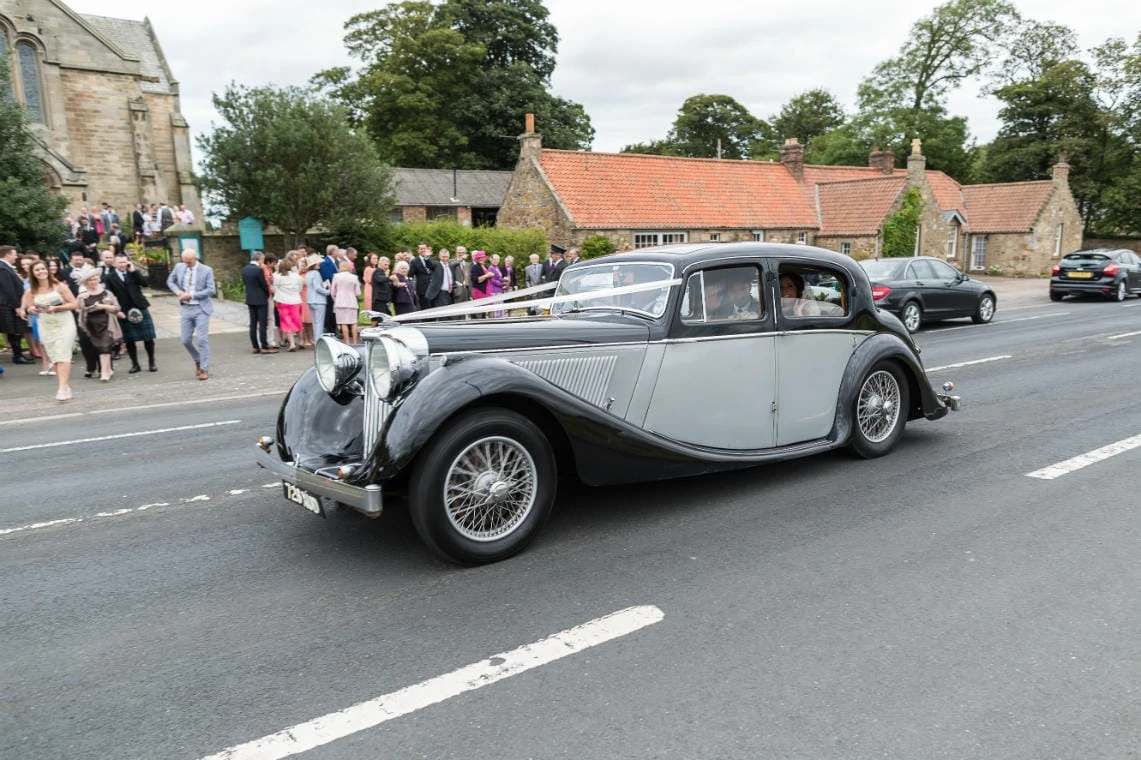 newlyweds depart at the church in East Lothian in a classic car