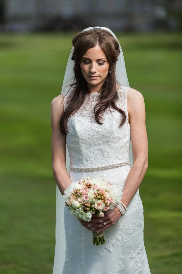 bridal portrait looking at her bouquet as she stands of the golf course at the hotel