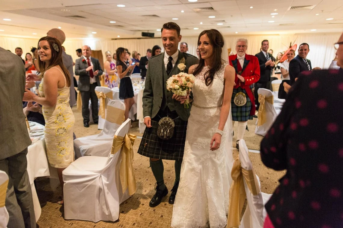 newlyweds are cheers by their guests as they make their way to the top table in the Dalmahoy Suite