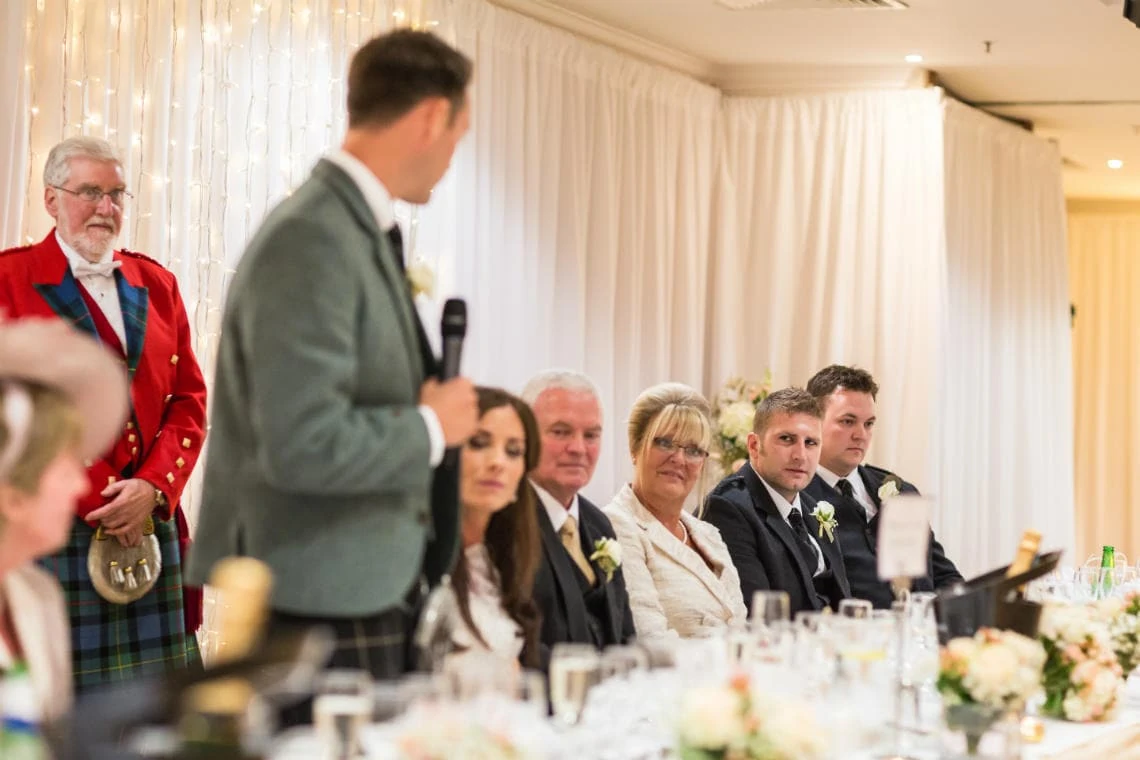top table guests listening to the groom's speech in the Dalmahoy Suite