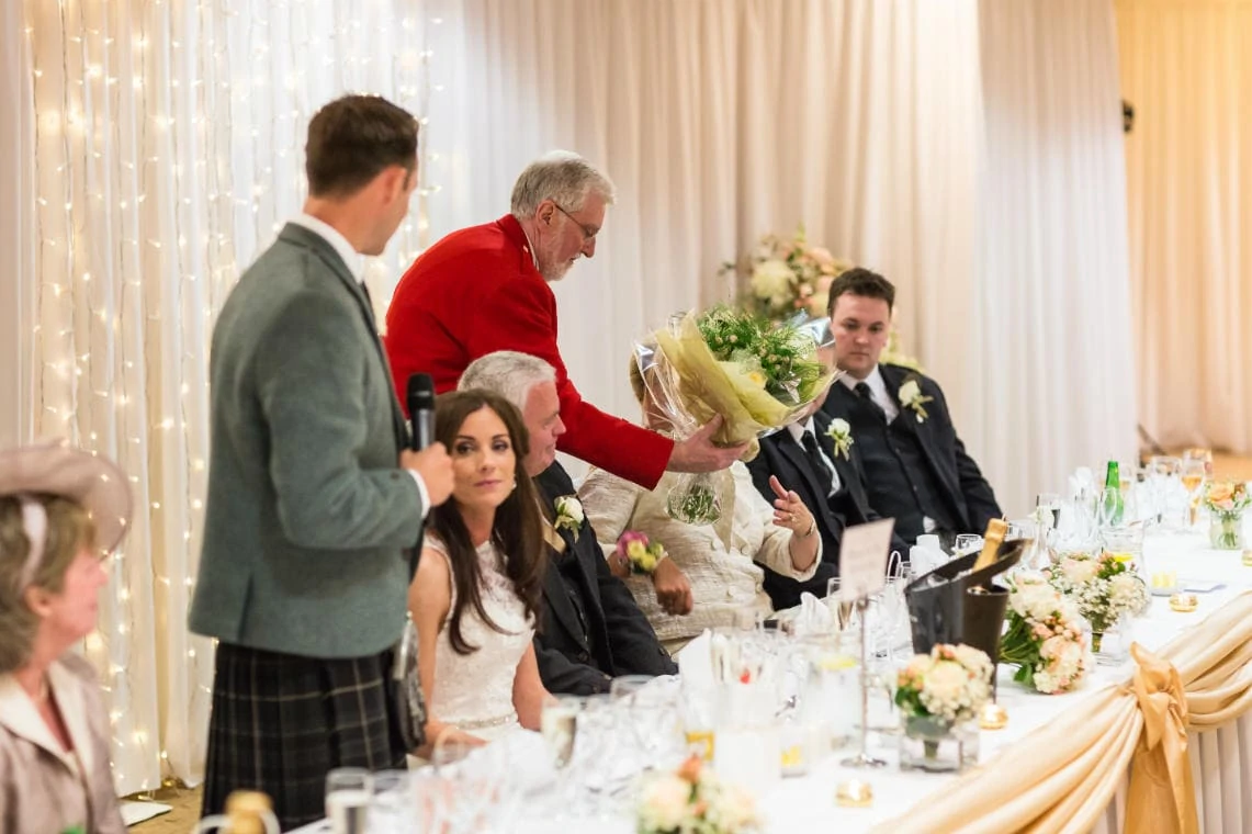 Toastmaster John presents a bouquet of flowers to the mother of the groom in the Dalmahoy Suite
