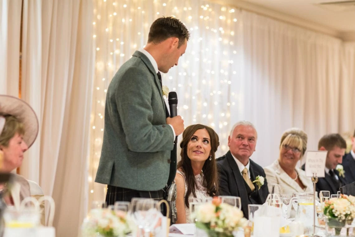 groom looks at his bride during his speech in the Dalmahoy Suite