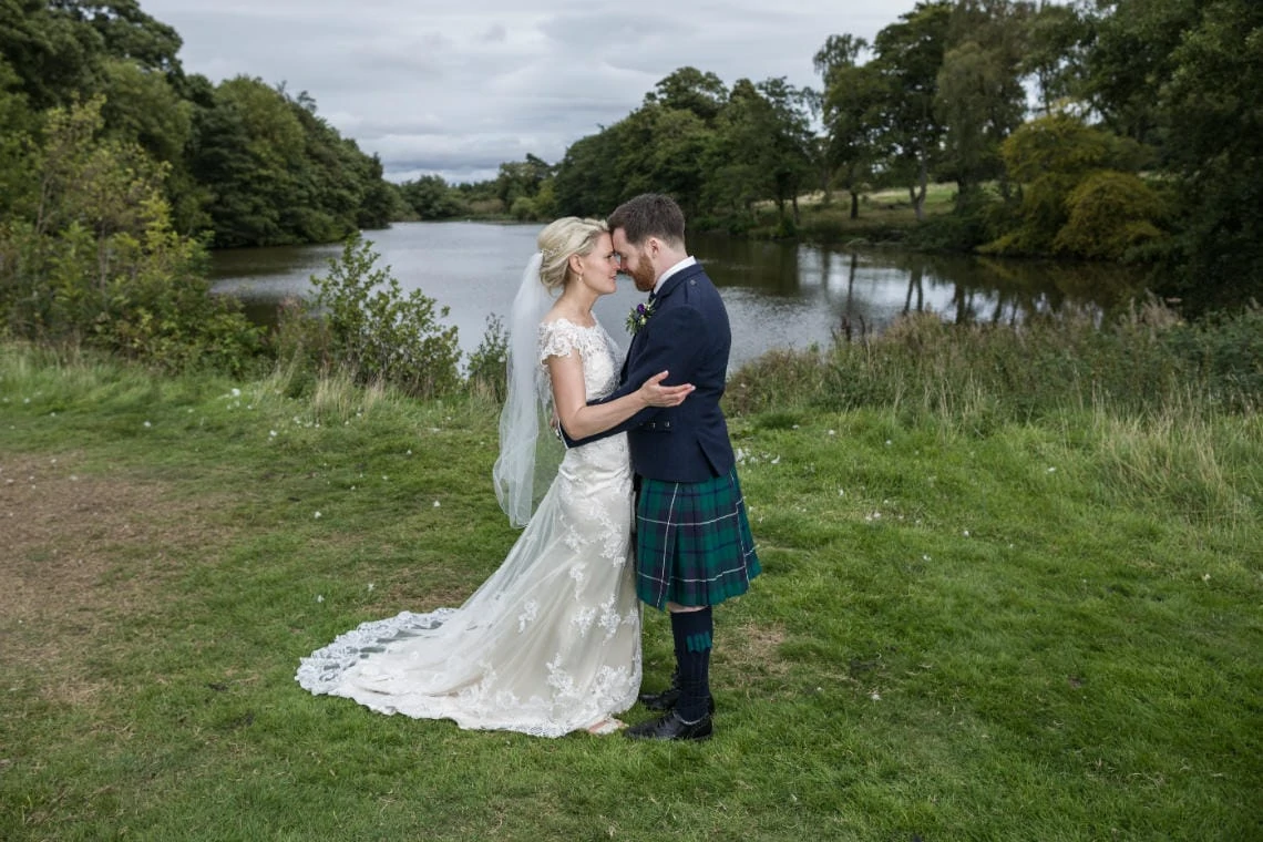 Golf course and grounds - newlyweds embrace in front of the pond