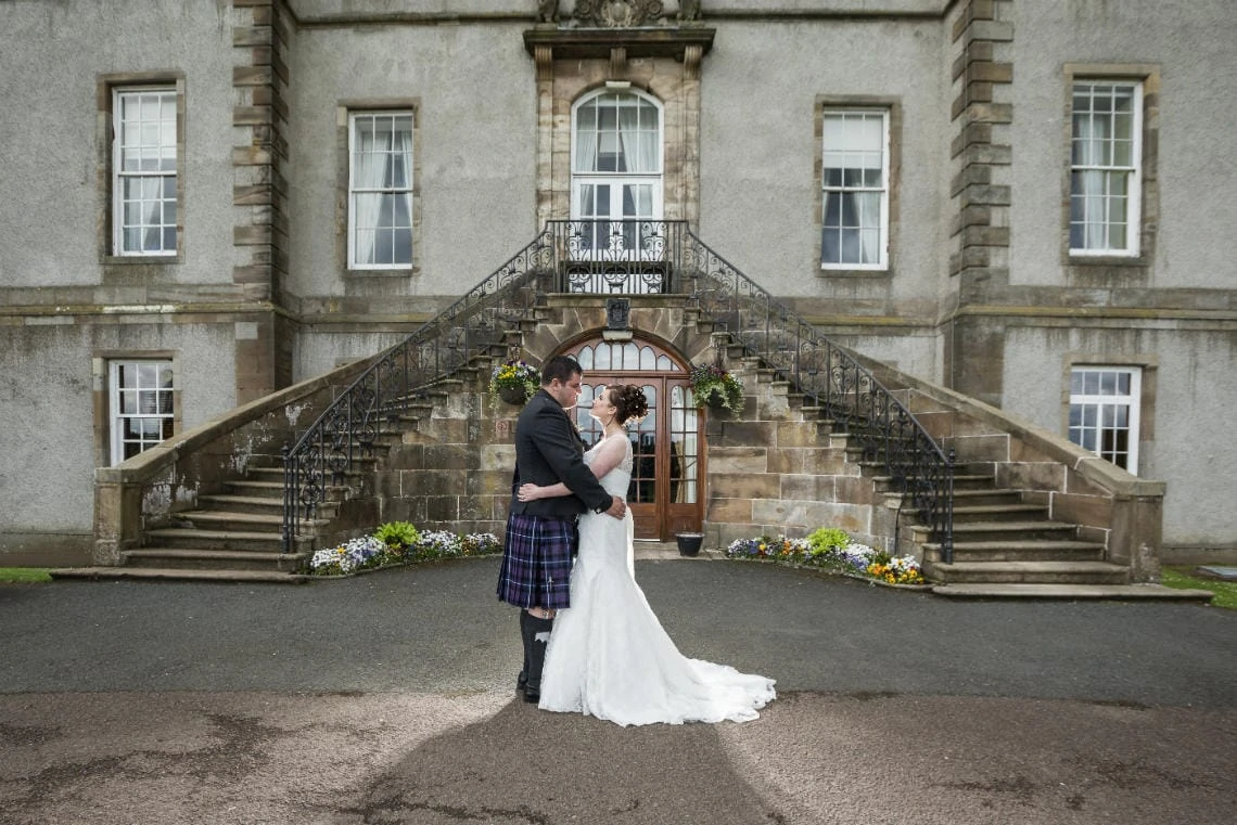 Golf course and grounds - newlyweds embrace in front of the staircase