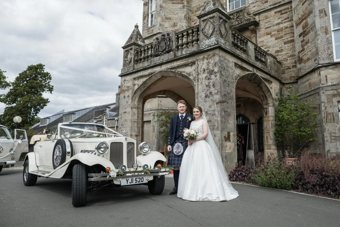Golf course and grounds - newlyweds standing by their classic car at the entrance