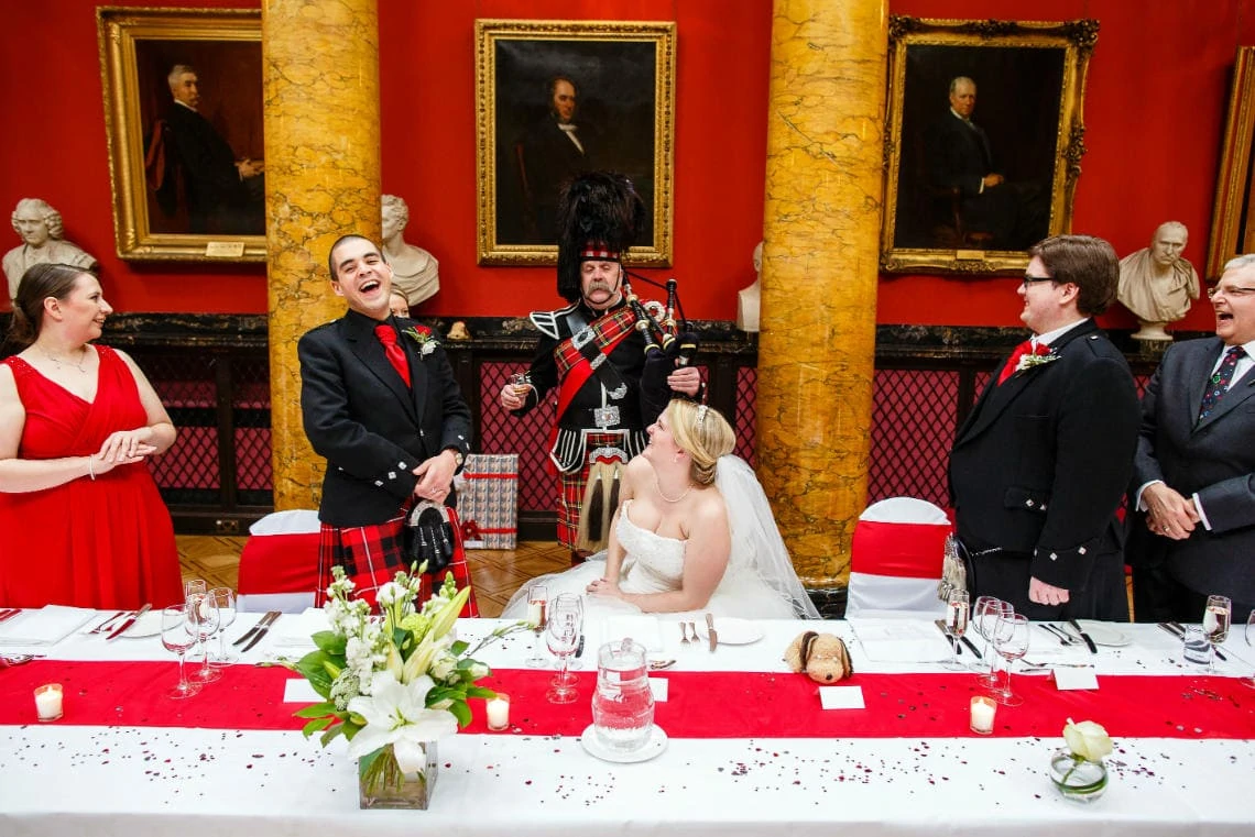 Great Hall newlyweds at top table with Piper Iain Grant