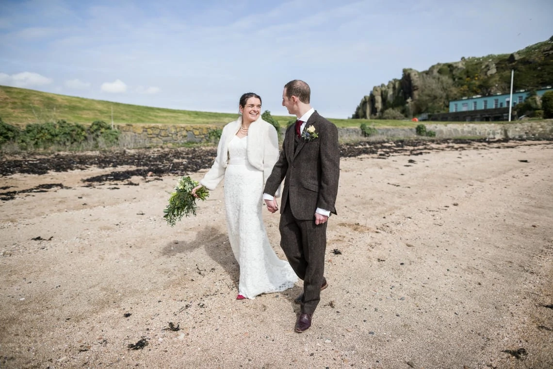 Newly-weds walking hand in hand on Inchcolm Island beach