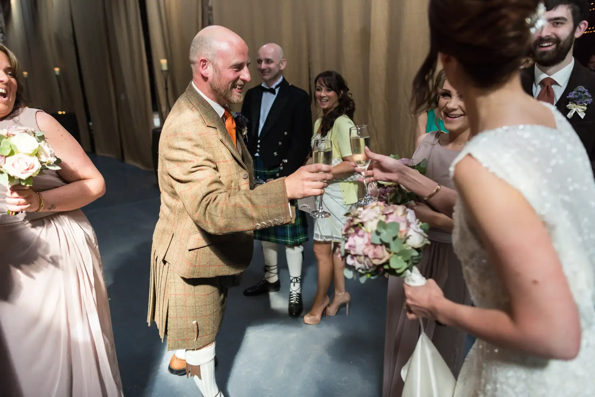 A joyful wedding reception scene with a bald man in a kilt toasting with a champagne glass, surrounded by smiling guests in formal attire.