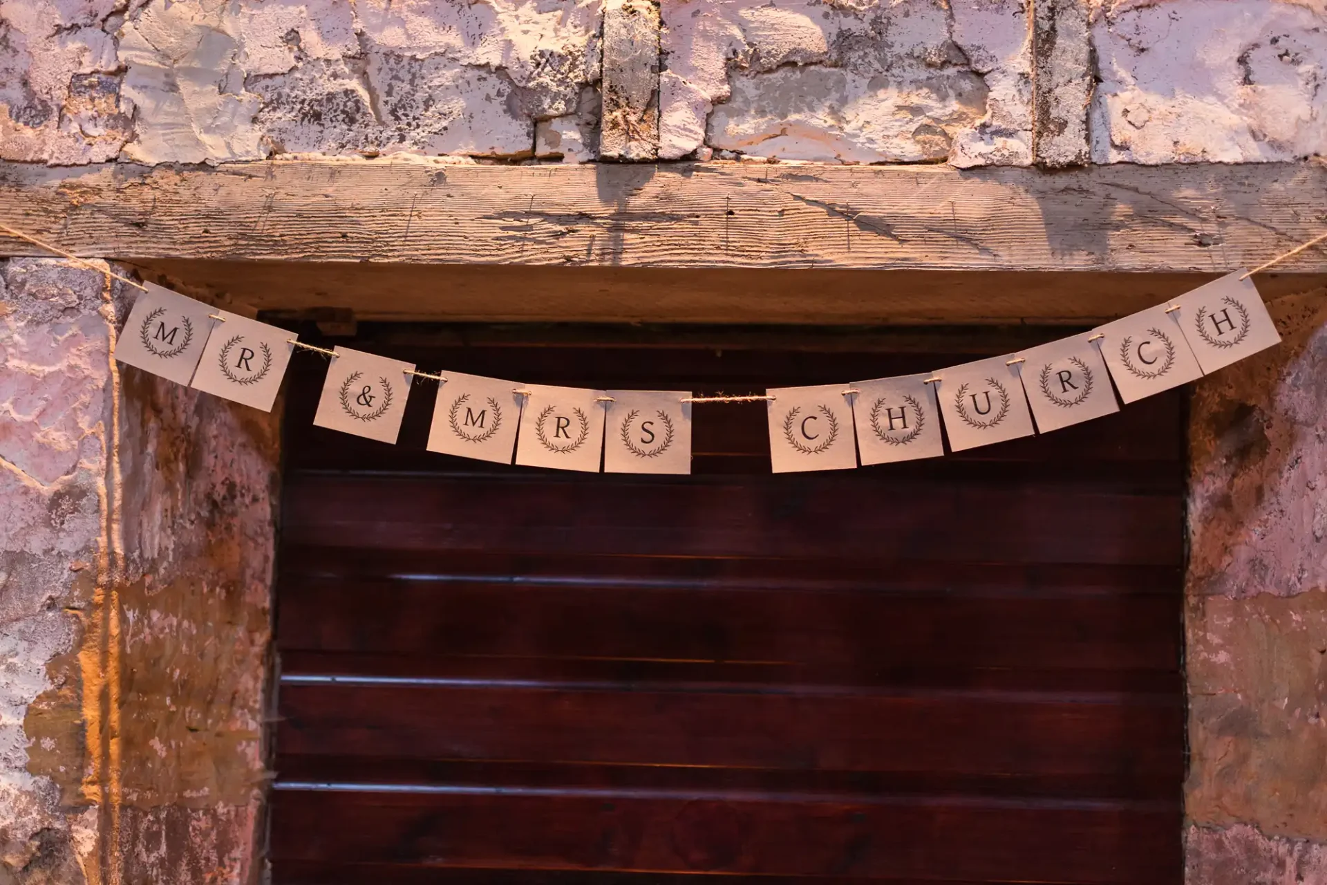 A banner reading "mr & mrs church" hangs on a rustic stone wall above a dark wooden door.