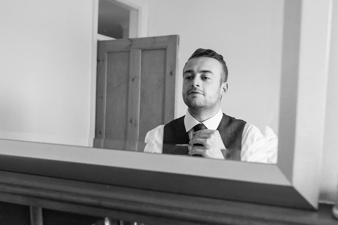 groom checking his tie in front of a mirror