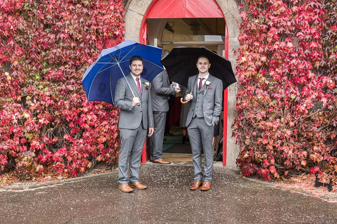 Liberton Kirk groomsmen waiting at the entrance under umbrellas