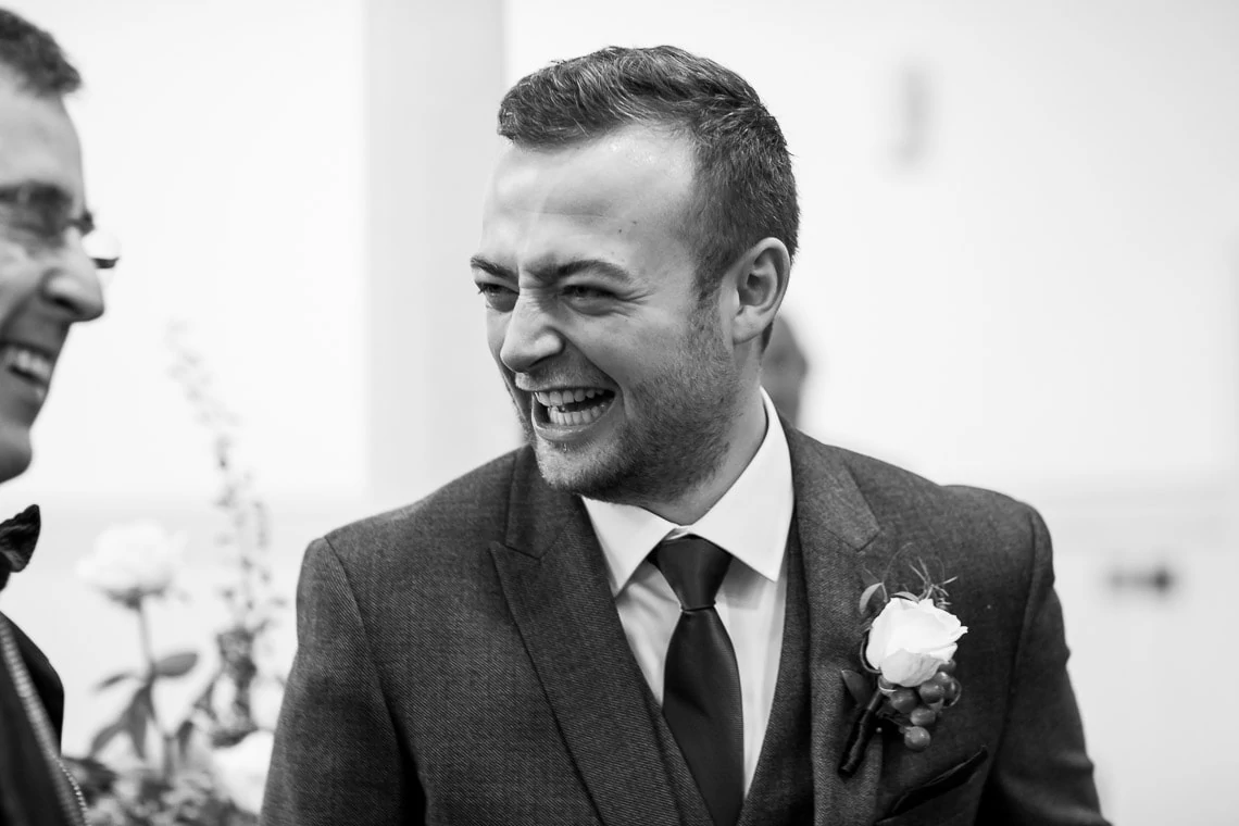 groom laughing as he chats with guests