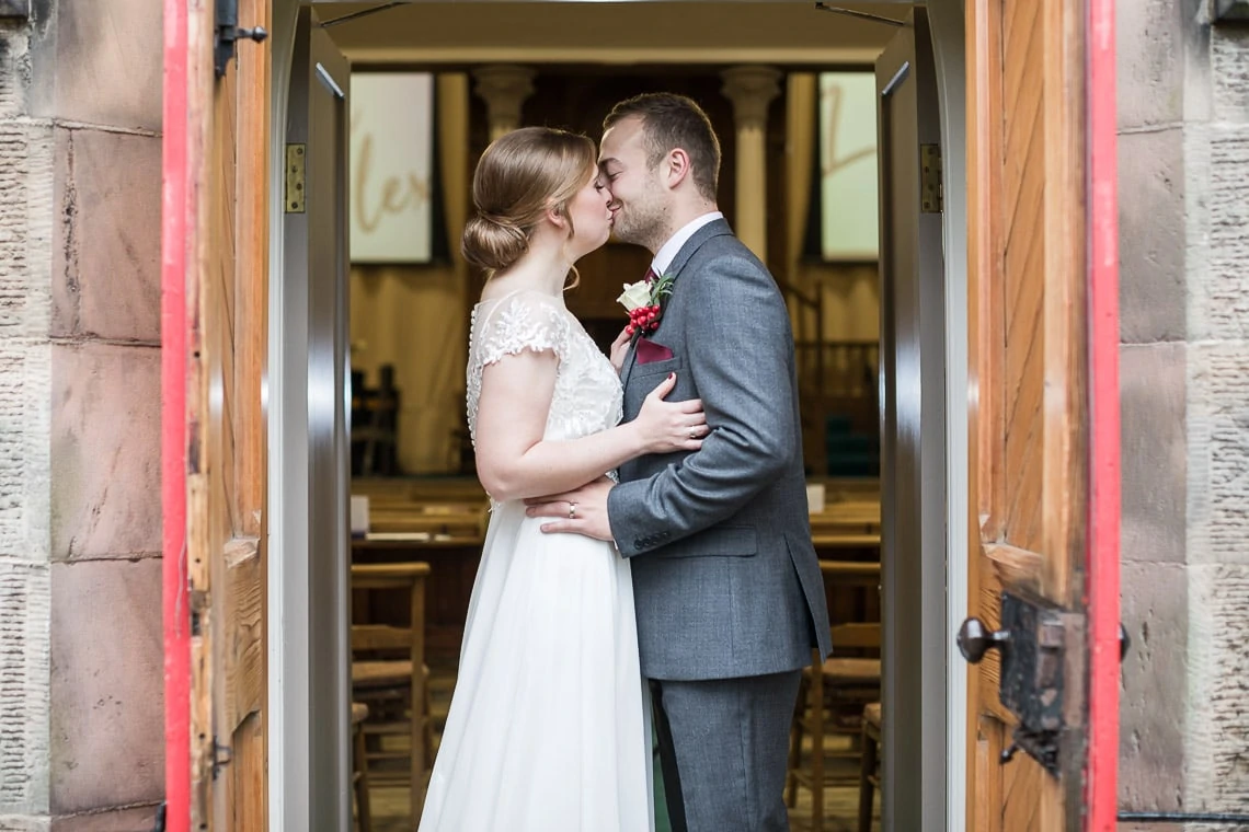 newlyweds kiss at the back door of Liberton Kirk