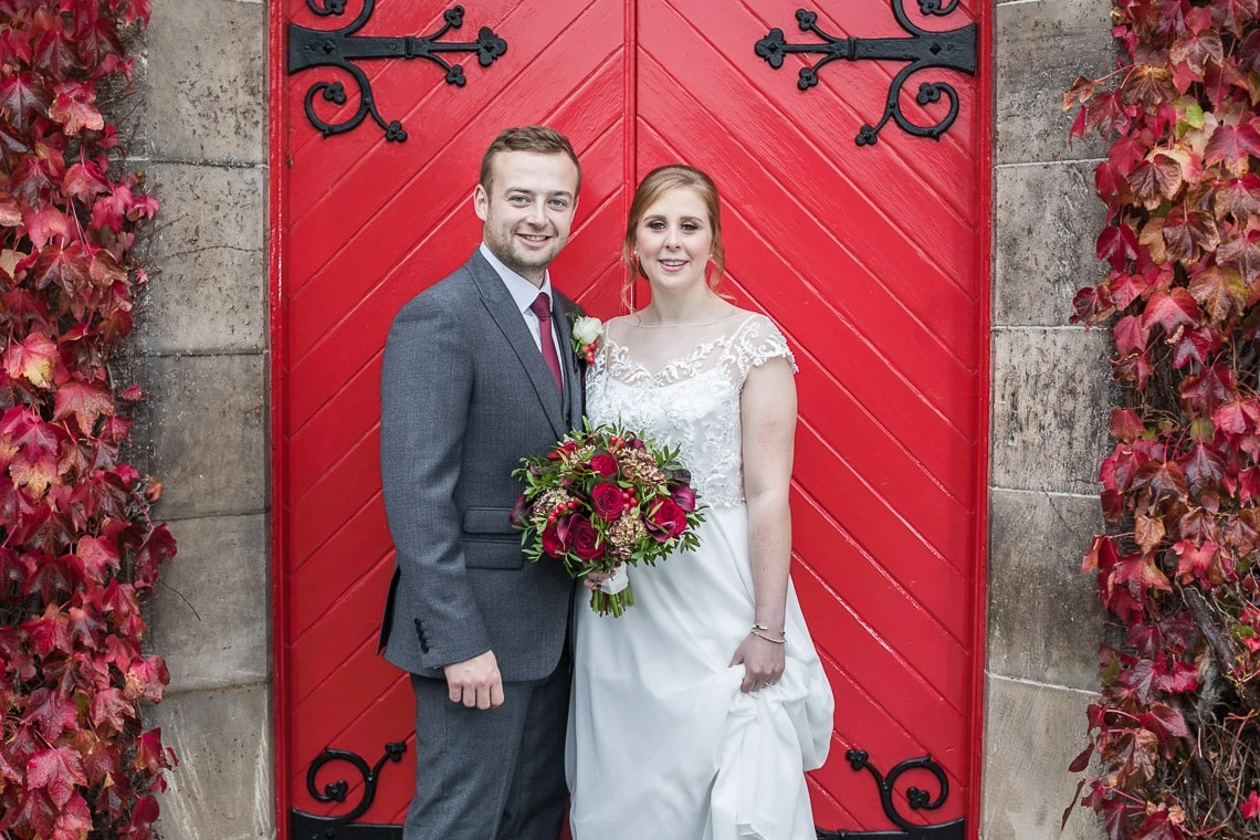 newlyweds in front of the red doors at Liberton Kirk