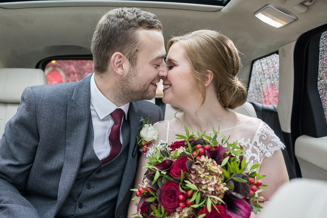 newlyweds embrace in the back of their wedding car